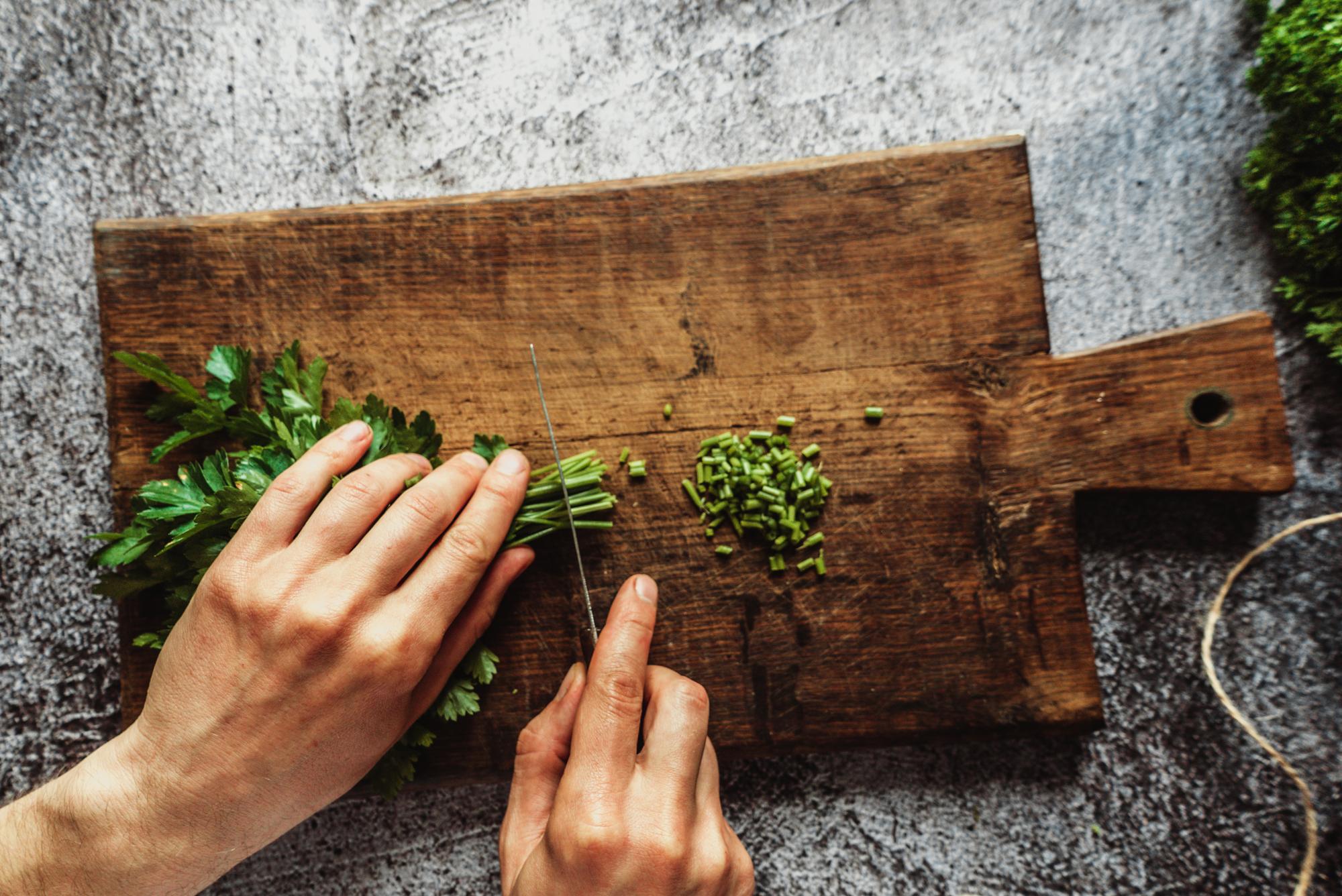 Chef arranging herbs on wooden board